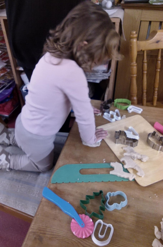Girl cuttinig animal shapes out of dough