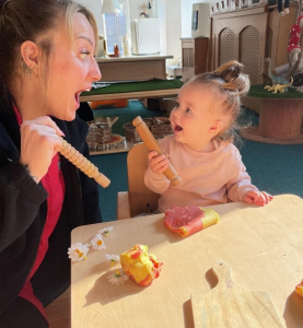 Whitstable Day Nursery staff member and young girl looking surprised whilst playing with  playdough together