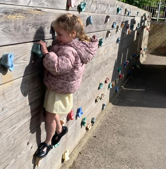 School girl playing outside on a climbing wall at St Marys Catholic Primary School